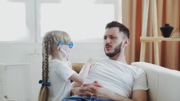 Daughter and father playing having fun together girl imagines herself to be doctor — Stock Video