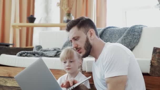 Szczęśliwy ojciec spędza czas ze swoją małą córką. Patrzą na notatnik. — Wideo stockowe