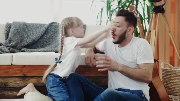 A menina brinca com o pai. Ela faz poses assustadoras e engraçadas — Vídeo de Stock
