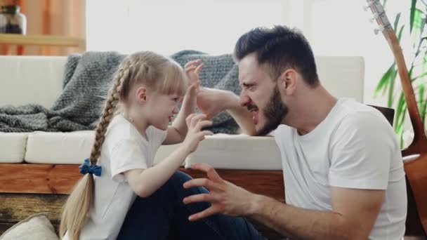 Kleines Mädchen spielt mit ihrem Vater. Sie macht beängstigende und lustige Posen — Stockvideo