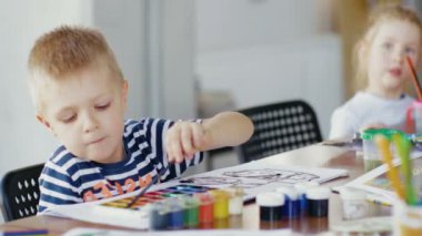 Küçük çocuk boya çiziyor. Çocuklar sınıfta resim çizer.