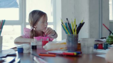 Pembe elbiseli şirin kız okulda resim çiziyor..