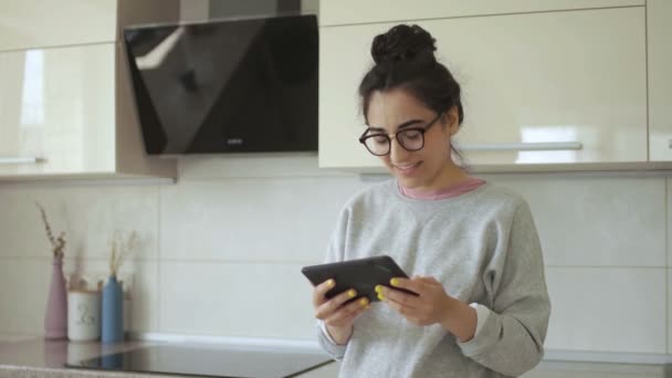 Mujer está viendo la película de comedia en la tableta en la cocina — Vídeos de Stock