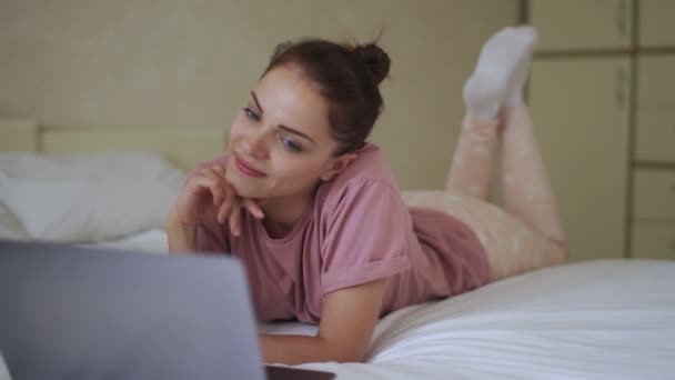 Mujer viendo la película en el ordenador portátil en la cama — Vídeo de stock