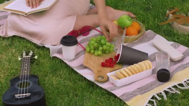 Chica picnic en el parque y la lectura de un libro . — Vídeo de stock