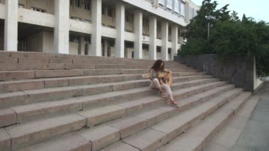 Üniversitenin yanındaki merdivenlerde akustik gitar çalan kadın.