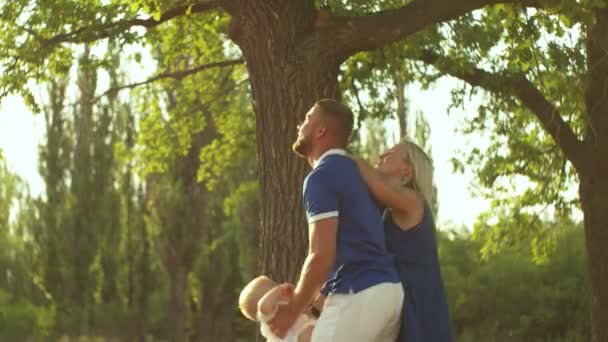 Glad far kaster sit barn op på haven mod solnedgangen – Stock-video