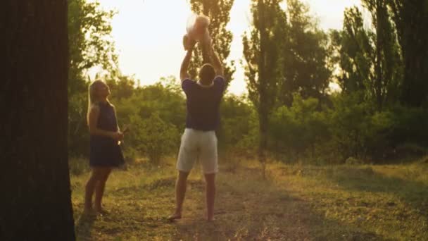 Lycklig pappa spyr upp sitt barn i parken mot solnedgången — Stockvideo