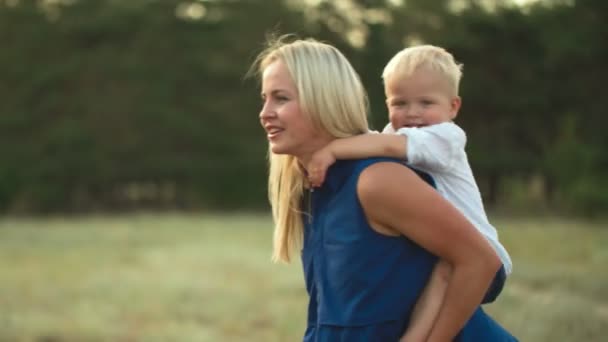 Boy piggybacking em suas mães de volta — Vídeo de Stock