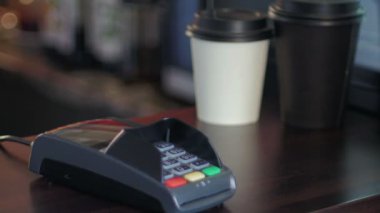Kafedeki genç adam bedelini akıllı bir telefon ve terminal kullanarak ödüyor.
