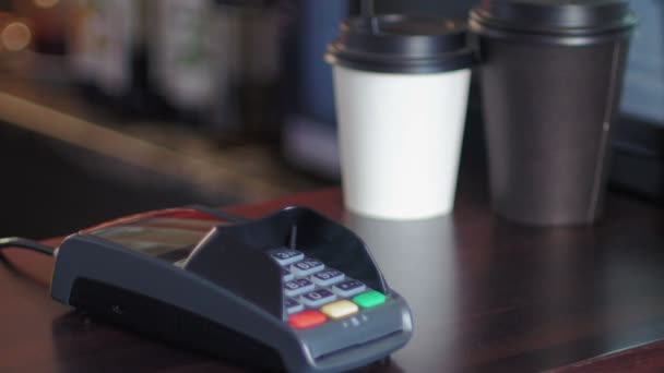 Медленное движение молодого человека в кафе оплачивается с помощью смартфона и терминала — стоковое видео