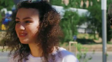 İki kıvırcık kız yaz parkında salıncakta sallanıyor ve konuşuyor..