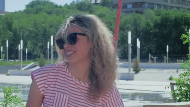 Twee lachende meisjes praten en rijden op een schommel in een zomerpark. — Stockvideo
