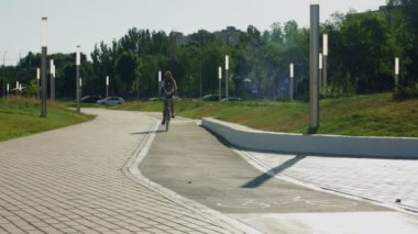 Genç kız parkta bisiklet sürüyor.