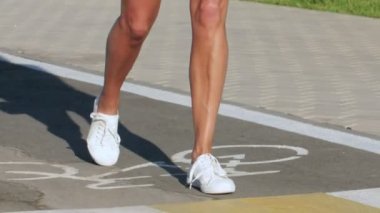 Genç bir kadın yaz parkında kaykayla yürüyor.