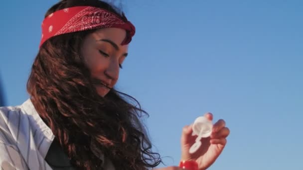 Mujer divirtiéndose soplando burbuja, cielo azul en el fondo — Vídeos de Stock