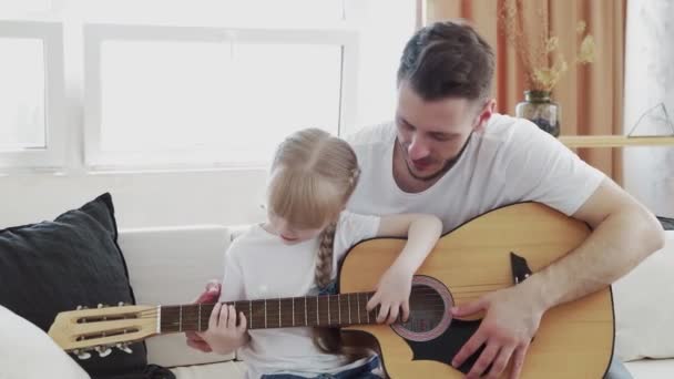 Jovem pai ensina filha a tocar guitarra em casa — Vídeo de Stock