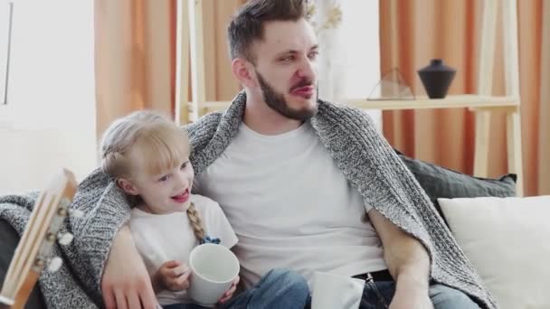 Jovem pai e sua filha se senta no sofá coberto com cobertor e fala — Vídeo de Stock