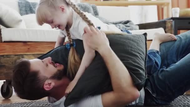 Pai feliz passar tempo com sua filha pequena. Deita-se no chão e abraços — Vídeo de Stock