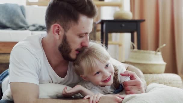 Glücklicher Vater und seine Tochter liegen auf dem Boden. Bärtiger Vater küsst seine kleine süße Tochter — Stockvideo