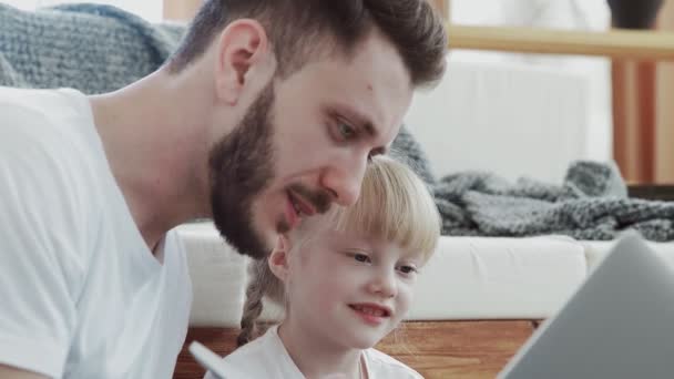 Feliz padre pasando tiempo con su pequeña hija. Están mirando el cuaderno. — Vídeos de Stock