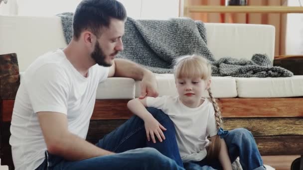 Lycklig far umgås med sin lilla dotter. De sitter på golvet och pratar. — Stockvideo