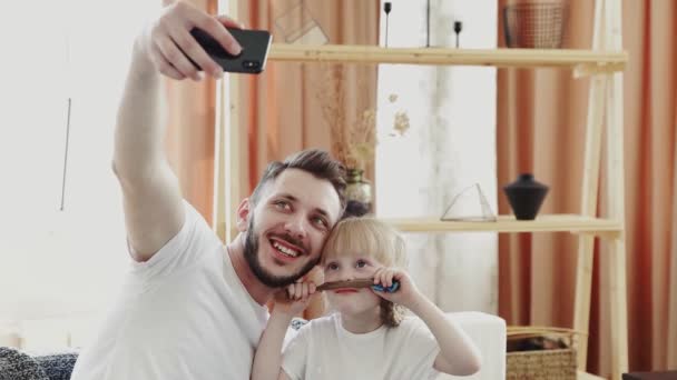 Jonge vader en zijn dochter neemt een selfie thuis — Stockvideo