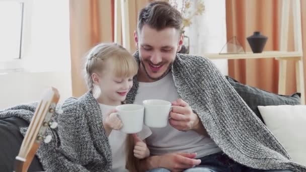 어린 아버지와 딸은 큰 흰색 컵으로 덮은 소파에 앉아 이야기를 나누고 있다 — 비디오