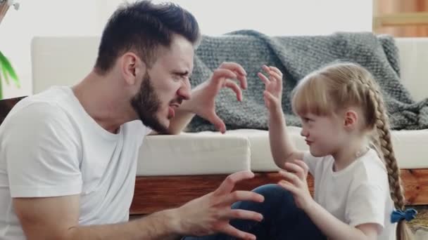 La niña juega con su padre. Ella hace poses aterradoras y divertidas. — Vídeo de stock