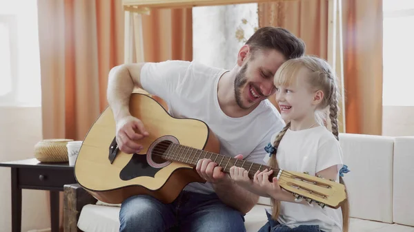 Joven padre e hija familia feliz pasar tiempo juntos tocando la guitarra en sala de estar calidez fondo de la casa . — Foto de Stock