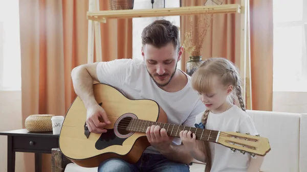 Jovem pai e filha família feliz passar o tempo juntos, tocando guitarra na sala de estar calor casa fundo . — Fotografia de Stock