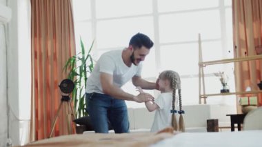 Genç baba küçük kızını döndürüyor.