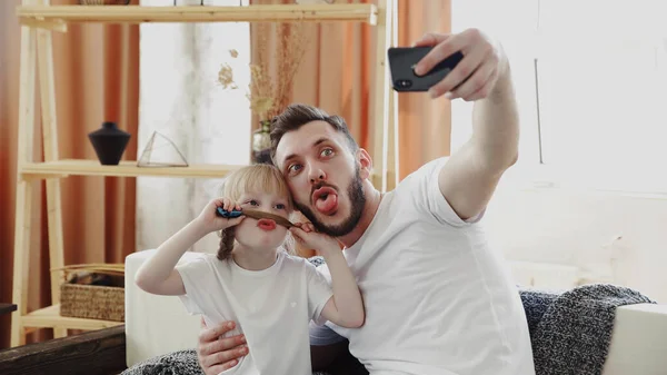 Retrato de una pequeña hija rubia y su padre, tienen bigote hecho de pelo. Toma una selfie. Día del Padre — Foto de Stock