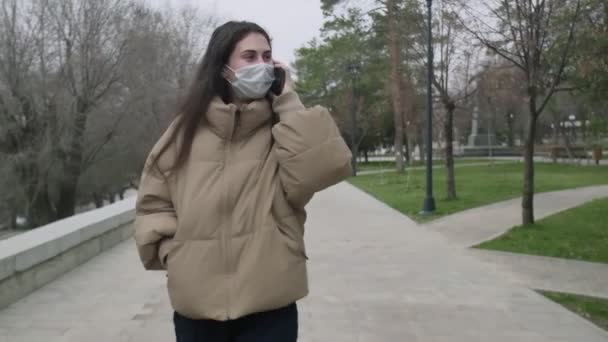 Hermosa mujer con máscara médica caminando y hablando por teléfono en el centro de una ciudad vacía Durante el Coronavirus COVID-19 Epidemia Pandémica Covid-19 coronavirus protección — Vídeo de stock