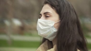 Virüsü korumak için tıbbi maske takan genç bir kadının yan görüntüsü. Konsept koronavirüs salgını, SARS, MERS, COVID-19, karantina, izolasyon süresi.