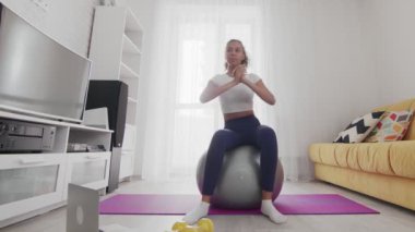 Genç Afro-Amerikan kadın spor eğitmeninin yardımıyla fitball üzerinde rotasyon egzersizi yapıyor.