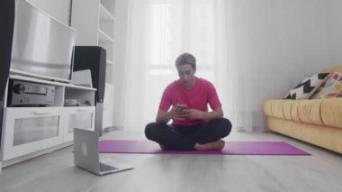 Makyajlı genç travesti homoseksüel adam online egzersizleri bitirdi ve telefon kullanmaya başladı.