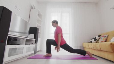Genç transseksüel homoseksüel adam yoga savaşçısı pozu veriyor.