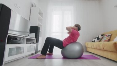 Makyajlı genç travesti homoseksüel adam evde spor yaparken karın kası egzersizi yapıyor.