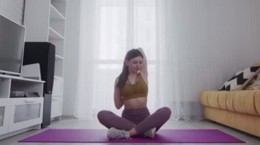 Dövmesi olan genç ve güzel bir kadın. Ellerini uzatıp, menekşe paspasın üstüne koyuyor.