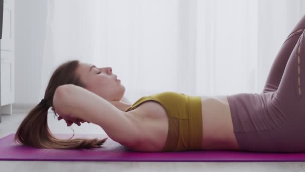 Jeune belle femme faisant abs crunch exercice sur tapis à la maison — Video