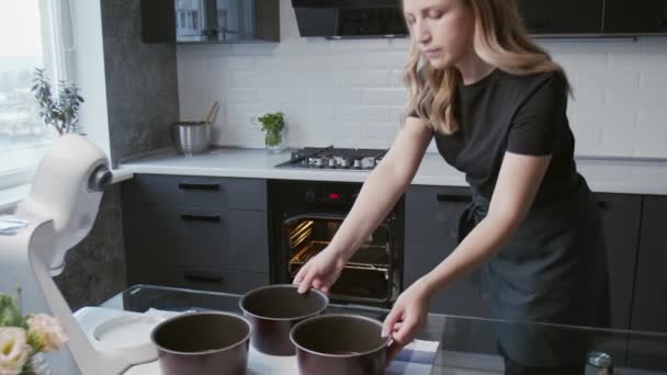 Professionell kock lagar tårta. Ung attraktiv hemmafru sätter i ugnen tre Bakeware Cake Pan med deg — Stockvideo