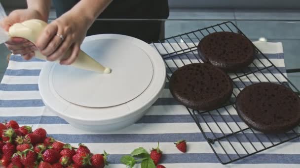 Profesyonel şef kek pişiriyor. Genç ve çekici ev hanımı tabağa beyaz krema koyar ve pastaya katar. — Stok video