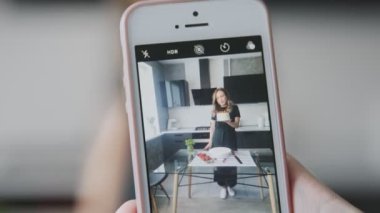 Şekerleme blogu. Birisi siyah tişörtlü, çilekle süslenmiş bir kadının fotoğrafını çekiyor..