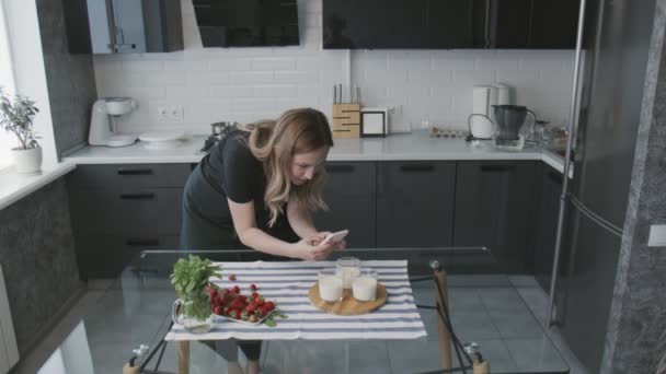 Süßwarenblog. Frau im schwarzen Hemd fotografiert Panna Cotta mit Orange — Stockvideo