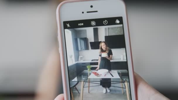 Konfektyr blogg. Någon tar bilder på kvinna i svart skjorta med tårta dekorerad med jordgubbe. — Stockvideo
