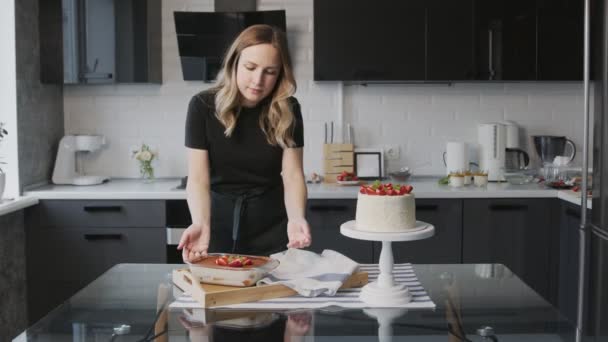 Profi-Koch kocht Kuchen. Frau stellt schöne weiße Torte mit Erdbeere, Panna Cotta und Tiramisu auf den Tisch — Stockvideo