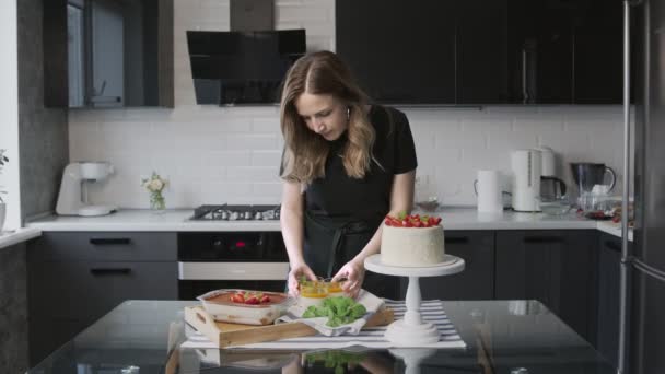 Profi-Koch kocht Kuchen. Schöne weiße Torte mit Erdbeere, Panna Cotta und Tiramisu auf dem Tisch — Stockvideo