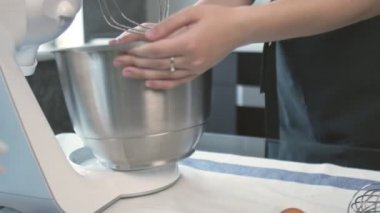 Profesyonel şef kek pişiriyor. Kadın ellerine yakın çekim, profesyonel miksere metal bir kase koyar.