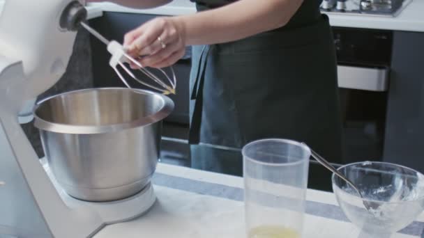 Chef profissional está cozinhando bolo. Jovem atraente dona de casa instal metal batedor no misturador profissional — Vídeo de Stock